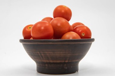 Taze kırmızı domatesler, beyaz arka planda koyu ahşap bir kasede istiflenmiş.