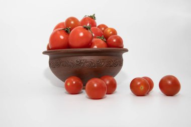 Taze kırmızı domatesler, temiz beyaz stüdyo arka planında sade ahşap kasede dizilmiş.