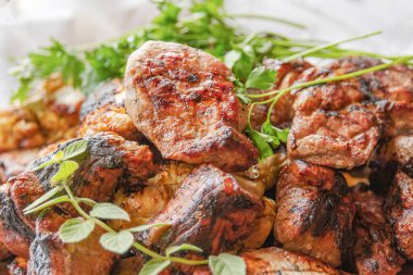 Tabakta taze otlarla servis edilen ızgara et parçaları lezzetli kırsal yemek sahneleri yaratıyor.