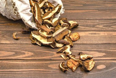 Kurutulmuş yabani mantarlar kırsal ahşap masaya dökülüyor.