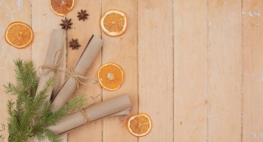 Noel parşömenleri köknar dalları, kurutulmuş portakallar ve ahşap arka planda baharatlar.