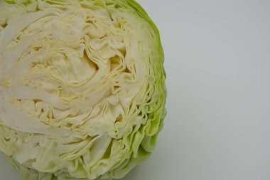 Taze yeşil lahana kesiti beyaz üzerinde izole edilmiş katmanlı yaprak dokusunu gösteriyor.