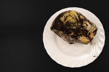 Gelişmiş mantar çürümesini gösteren ağır küflü ekmek somunu siyah arka planda izole edilmiş.
