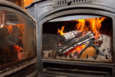 Şöminenin içinde yanan odun dökme demir şömine sıcak ve rahat bir ev atmosferi yaratır.