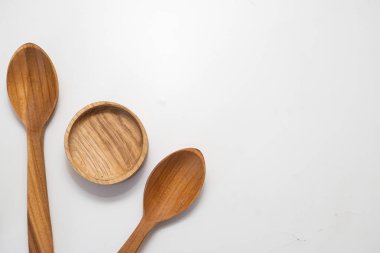 Ahşap mutfak kepçeleri ve yuvarlak kaseler beyaz arka planda simetrik olarak dizilmiş.