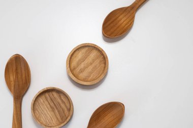 Ahşap mutfak kepçeleri ve yuvarlak kaseler beyaz arka planda simetrik olarak dizilmiş.