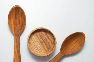 Ahşap mutfak kepçeleri ve yuvarlak kaseler beyaz arka planda simetrik olarak dizilmiş.