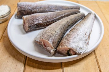 Çiğ balık parçaları beyaz tabakta baharatlı pişirmek için hazırlandı.