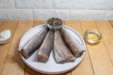 Çiğ balık parçaları beyaz tabakta baharatlı pişirmek için hazırlandı.