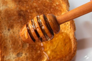 Beyaz tabak ahşap masada ballı ekmek dilimi.