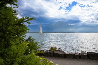 Sakin Dağ Gölü 'nde dramatik bulutlar ve uzak tepelerle yelkenli.