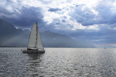 Dağ Gölü 'ndeki yelkenli gemi dramatik fırtına bulutları ve Alp manzarası altında