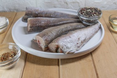 Çiğ hake balığı ev yemeği için beyaz tabakta hazırlandı.