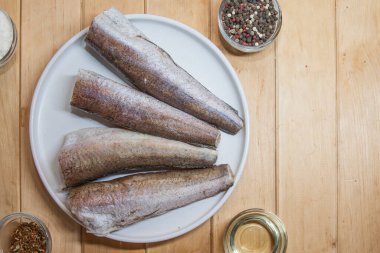 Çiğ hake balığı ev yemeği için beyaz tabakta hazırlandı.