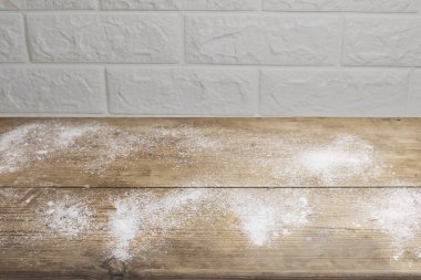 Beyaz tuğla duvara saçılmış un ile ahşap mutfak masası.
