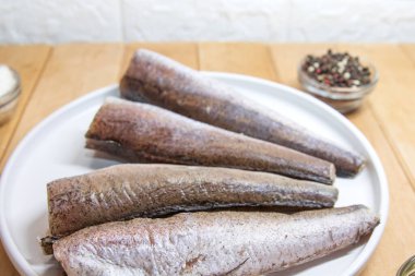 Çiğ hake balığı ev yemeği için beyaz tabakta hazırlandı.