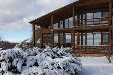 Karlı kış bahçesiyle çevrili geniş pencereli modern ahşap ev