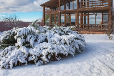 Karlı kış bahçesiyle çevrili geniş pencereli modern ahşap ev