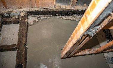 Banyo tadilatı sırasında temiz beton döşeme görünür tesisat ve ahşap yapı ile döşenmiş.