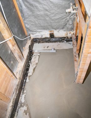 Banyo tadilatı sırasında temiz beton döşeme görünür tesisat ve ahşap yapı ile döşenmiş.