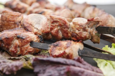 Üstünde marul yaprakları olan ızgara et şişleri.