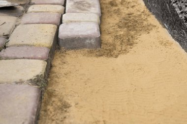 Beton kaldırım taşlarının kenarı. Yaya yolu boyunca kum tabanı var.