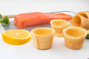 Somon filetosu ve beyaz arka planda avokado soslu waffle konileri.