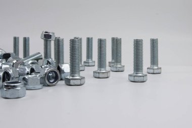 Metal civatalar ve uğursuz fındıklar endüstri için beyaz arka plana saçılmış.