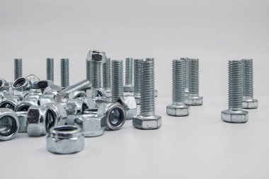 Metal civatalar ve uğursuz fındıklar endüstri için beyaz arka plana saçılmış.