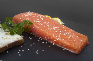 Koyu tahta kenarında limon dilimli çiğ somon filetosu.