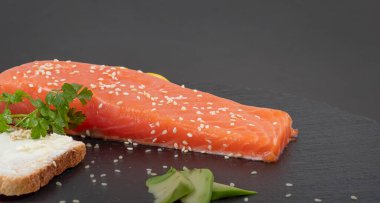 Koyu tahta kenarında limon dilimli çiğ somon filetosu.