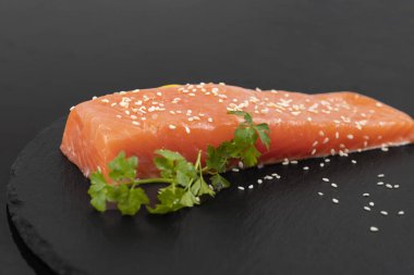 Koyu tahta kenarında limon dilimli çiğ somon filetosu.