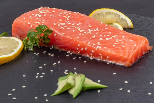 Koyu tahta kenarında limon dilimli çiğ somon filetosu.