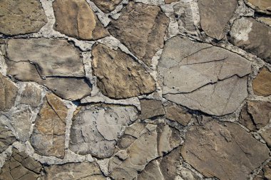 Direk güneş ışığı altında düzensiz duvar desenli doğal taş duvar dokusu.