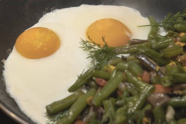 Karışık sebzeli kızarmış yumurta yeşil fasulye mantarı ve kızartma tavasında pişen otlar.