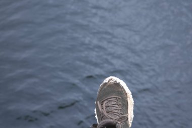 İnsan ayağı karanlık su yüzeyinde riskli bir adım atıyor. Bu da hata ve yanlış kararı simgeliyor.