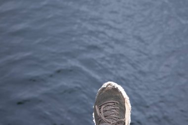 İnsan ayağı karanlık su yüzeyinde riskli bir adım atıyor. Bu da hata ve yanlış kararı simgeliyor.