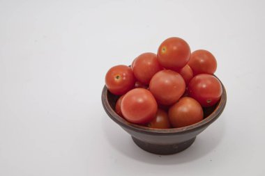 Beyaz arka plan görünümlü seramik kasede istiflenmiş domatesler.