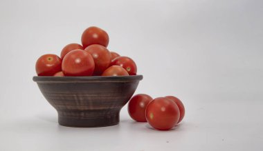 Beyaz arka plan görünümlü seramik kasede istiflenmiş domatesler.