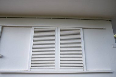 Binanın dış cephesinde beyaz pencere panjurları var.