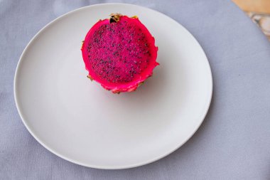 Olgun ejderha meyvelerinin yarısı en az kompozisyonda beyaz plaka üzerine kuruludur.