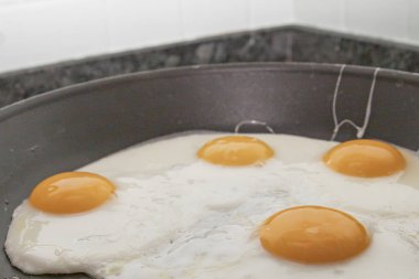 Dört yumurta, parlak yumurta sarısı, yapışmaz tavada pişiyor.