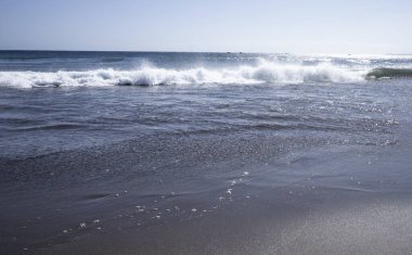 Islak kumlu sahilde hafif deniz dalgaları minimum doğal arka plan oluşturur.