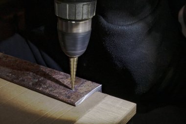 Tezgahta elektrikli matkap kullanarak matkap ucu ile metal plaka delme