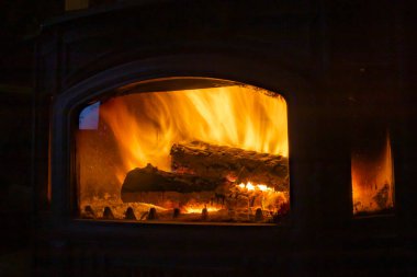 Metal sobanın içinde odun yakmak ev ısıtması ve sıcak ışık sağlıyor.