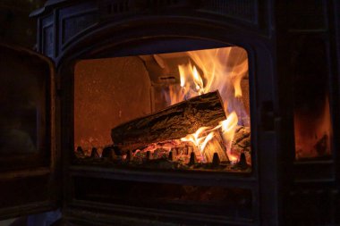 Işıl ışıl közlerle yanan demir odun sobası dök ve kapalı alanda ateş yak.