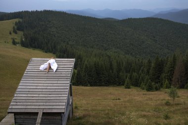 Dağ manzaralı ve orman manzaralı ahşap bir kulübede dinlenen kadın.