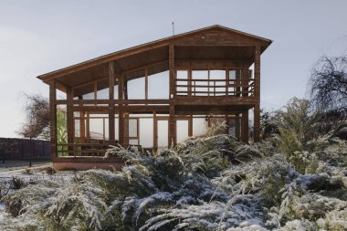 Kışın bahçesinde geniş pencereleri olan modern ahşap ev.