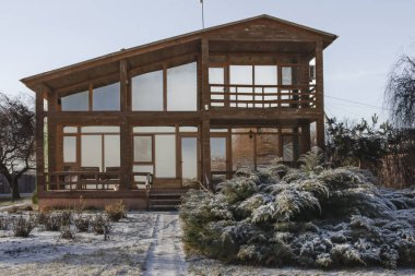Kışın bahçesinde geniş pencereleri olan modern ahşap ev.