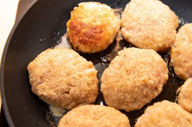 Ev yemeği sırasında tavada kızartılmış çiğ tavuk pirzolası.